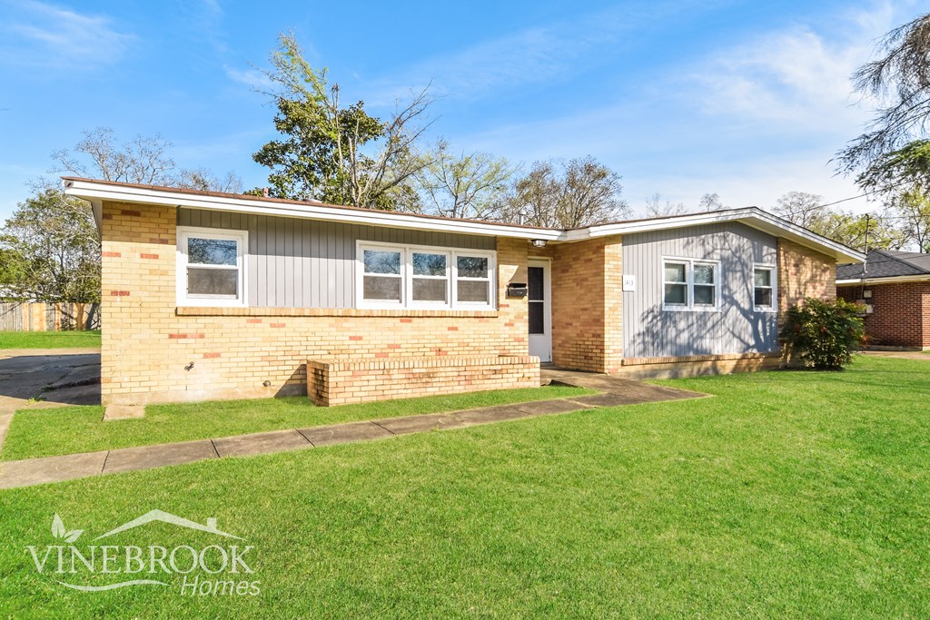 A house with a lawn in front and a sign that says Vinebrook Homes.