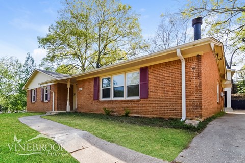 A brick house with a chimney and a sign that says Vinebrook Homes.