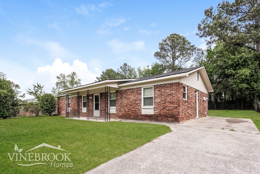 A brick house with a gravel driveway in front.