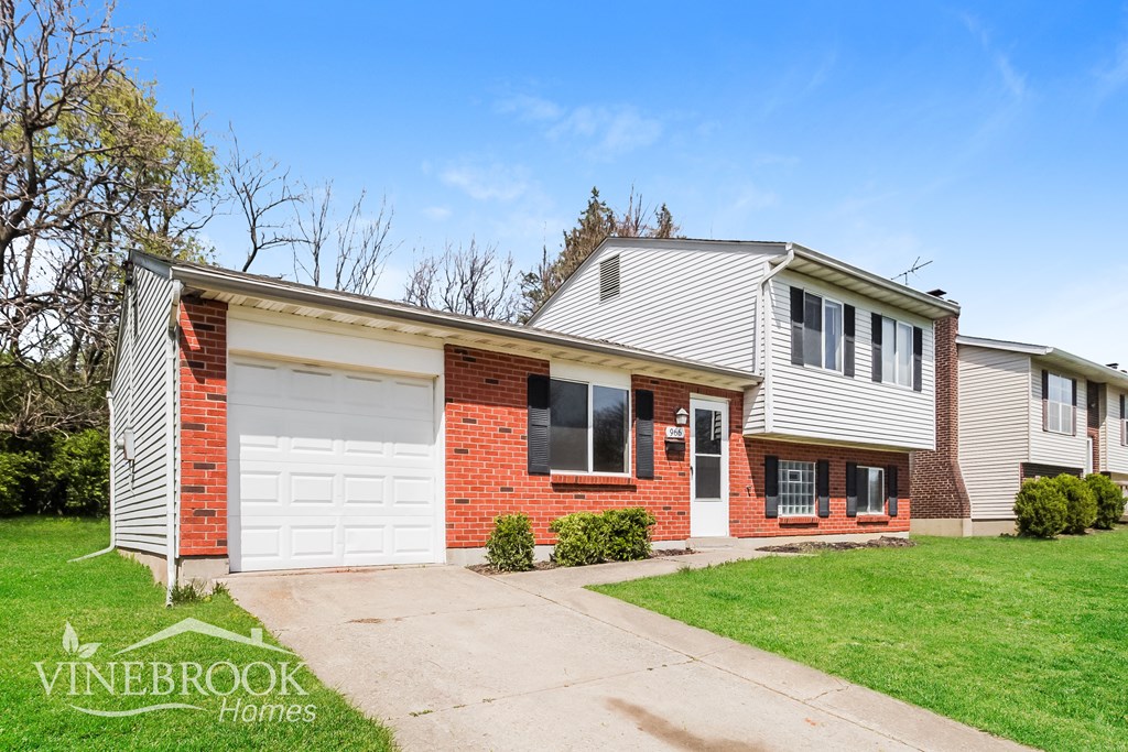 A house with a red brick wall and a white garage door is for sale.