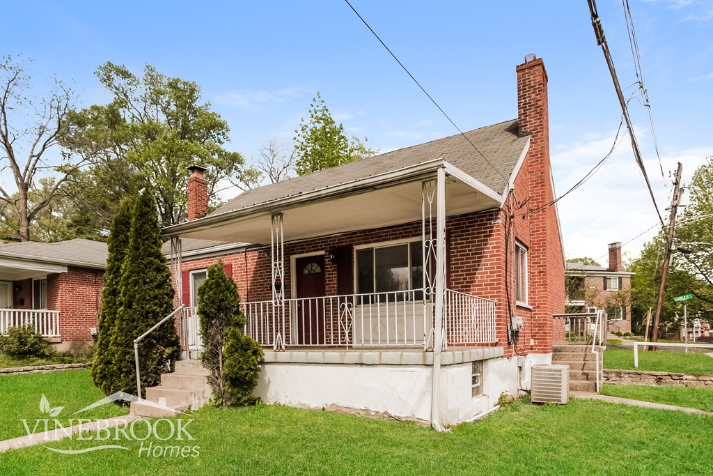 A red brick house with a porch and a sign that says Vinebrook Homes.