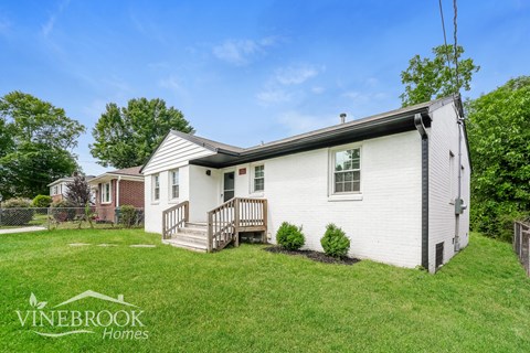 A white house with a porch and a sign that says Vinebrook Homes.
