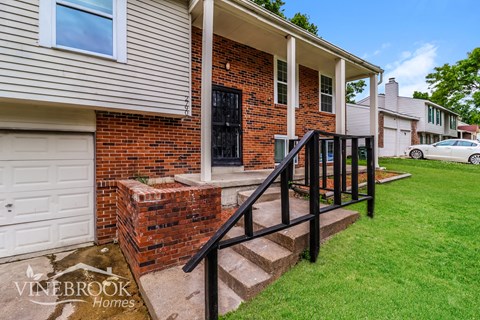 A house with a brick facade and a white garage door is for sale.