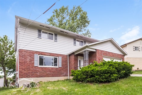 A house with a red brick wall and a white siding.
