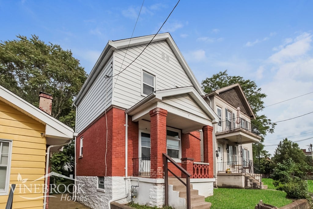 A house with a red brick chimney is in front of a yellow house.