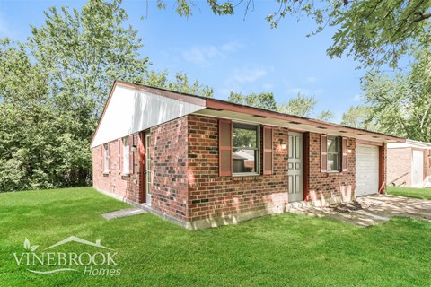 A brick house with a white roof and a green lawn in front.