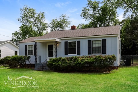 A white house with a black roof and a sign that says Vinebrook Homes.