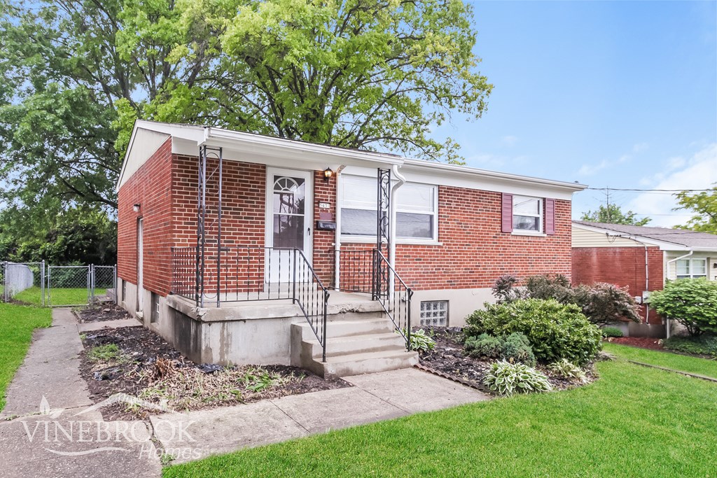 A red brick house with a white door and a small front yard.