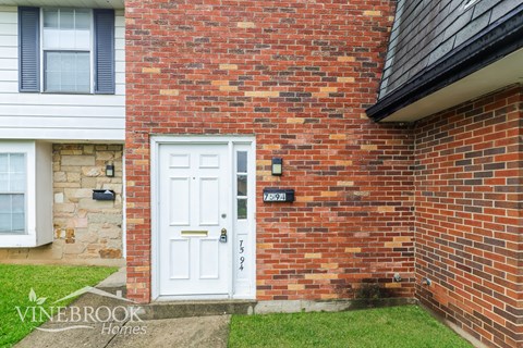 A white door with a black handle is on a brick wall.