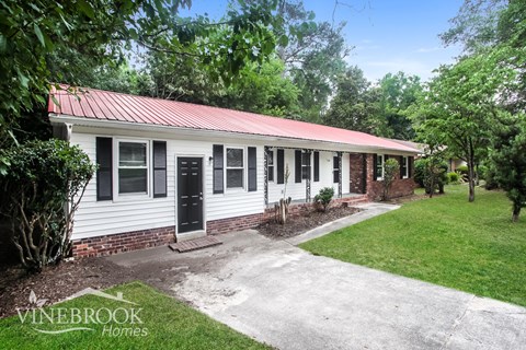 A house with a red roof and a sign that says Vinebrook Homes.