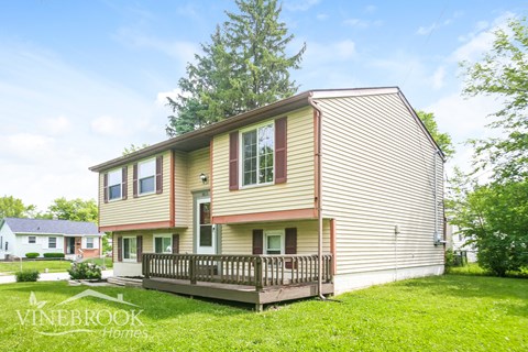 A two-story house with a porch and a tree in the front yard.
