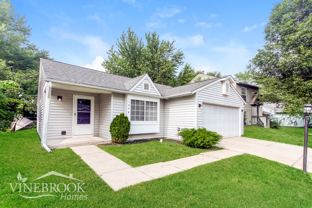 A Vinebrook Homes house with a blue door and a small front yard.
