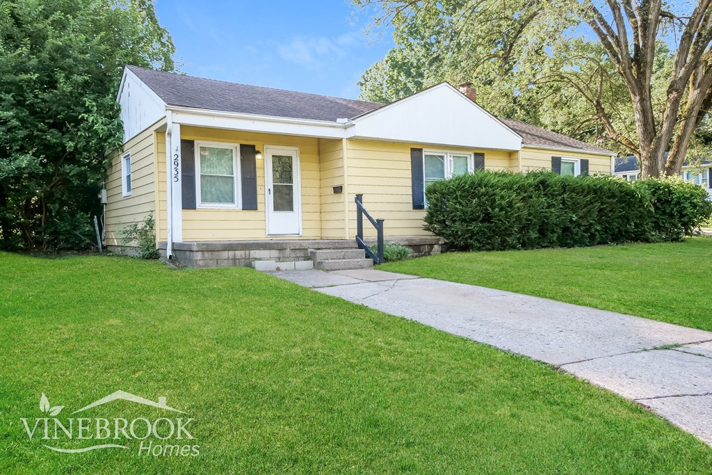 A yellow house with a sign that says Vinebrook Homes.