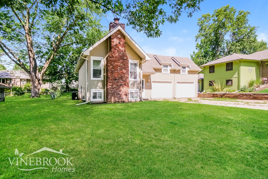 A house with a green lawn and a tree in front of it.