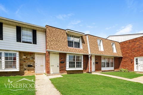 A row of houses with the first one having a sign that says Vinebrook Home.