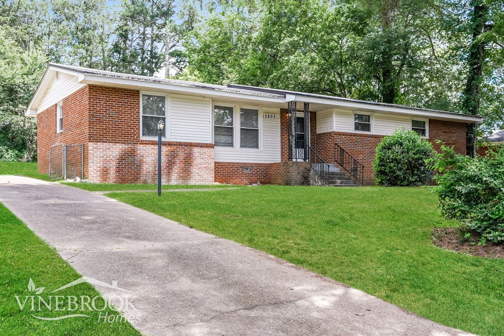 A brick house with a white roof and a white fence.