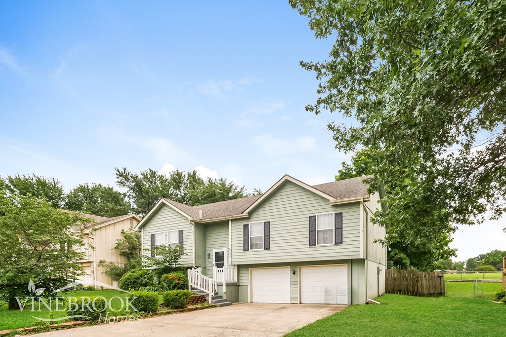 A house with a garage is surrounded by greenery.