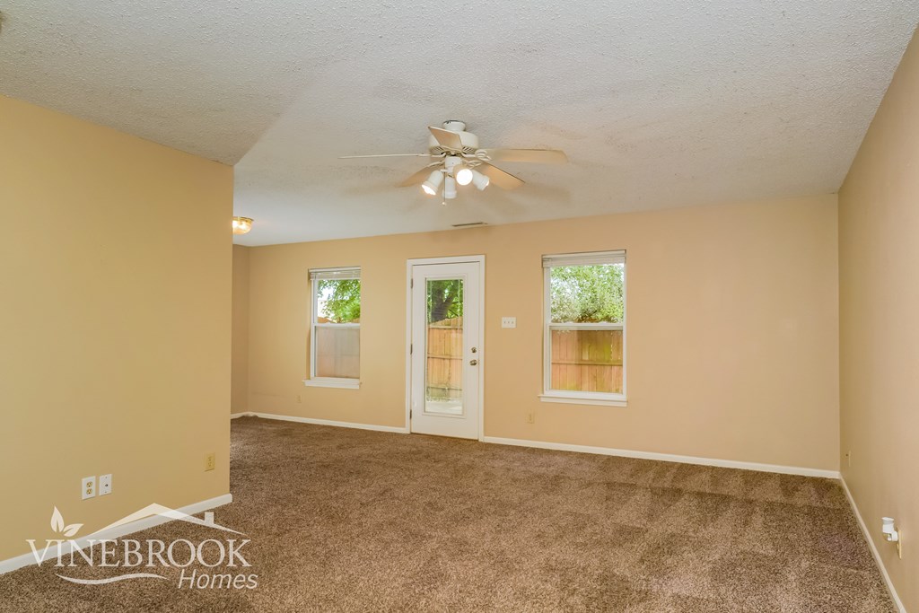 A room with a carpeted floor and a ceiling fan.