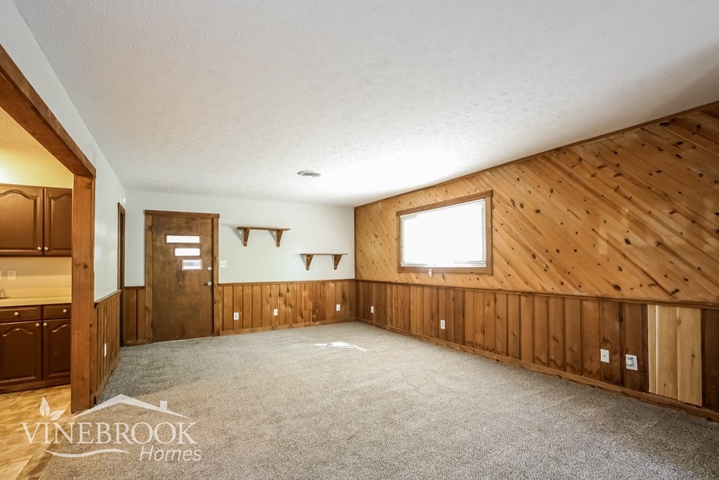 A large empty room with wooden walls and a carpeted floor.