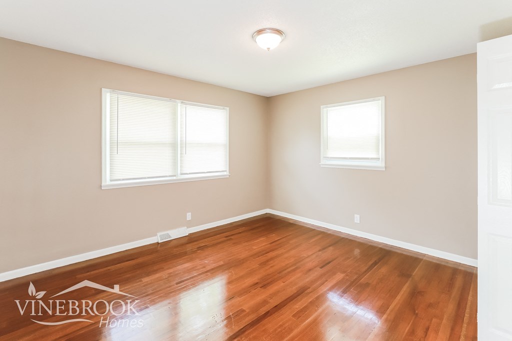the living room of a home with a hardwood floor and two windows