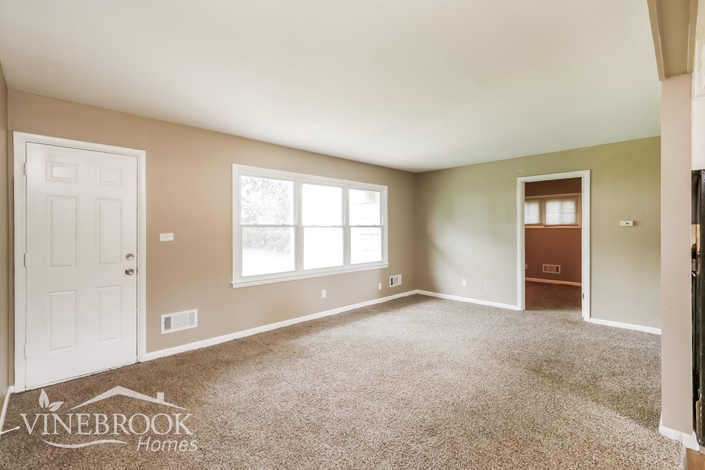 an empty living room with carpet and a white door
