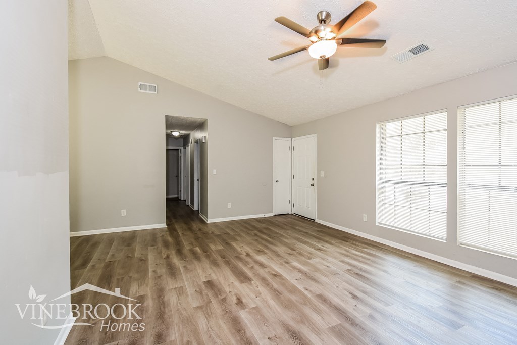 an empty living room with wood floors and a ceiling fan