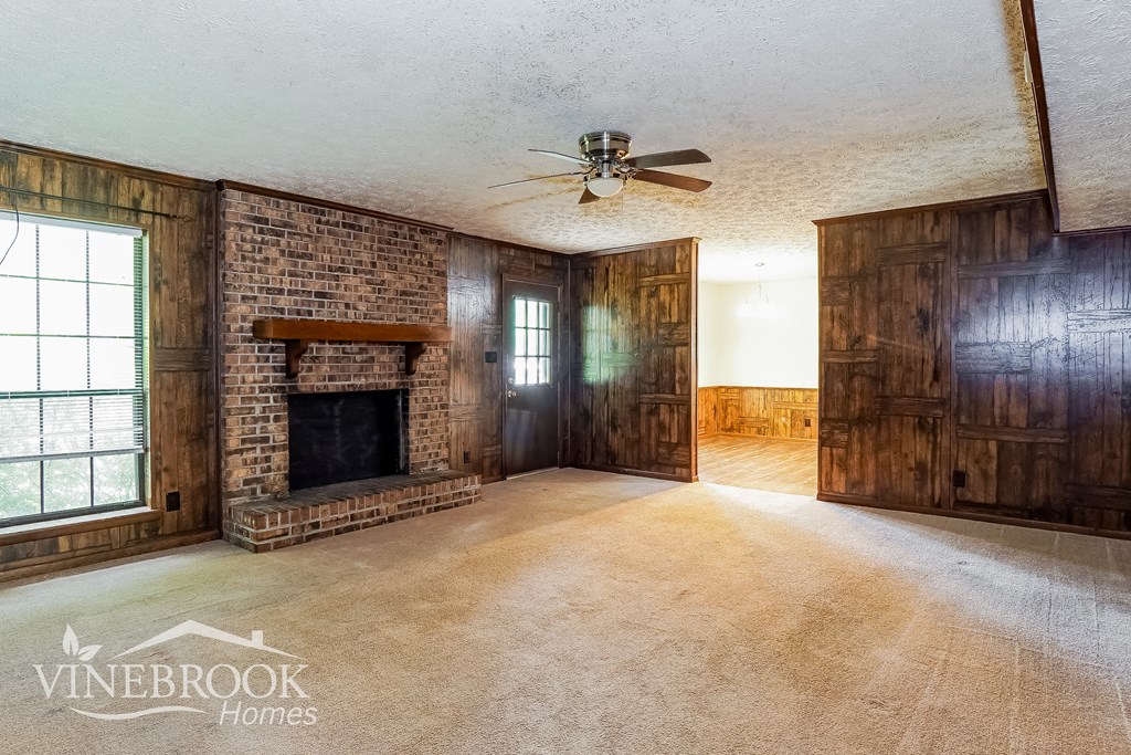 a living room with a brick fireplace and a ceiling fan