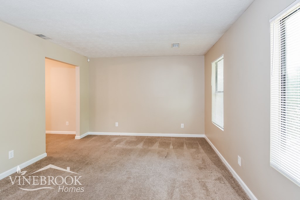 a living room with a carpeted floor and two windows