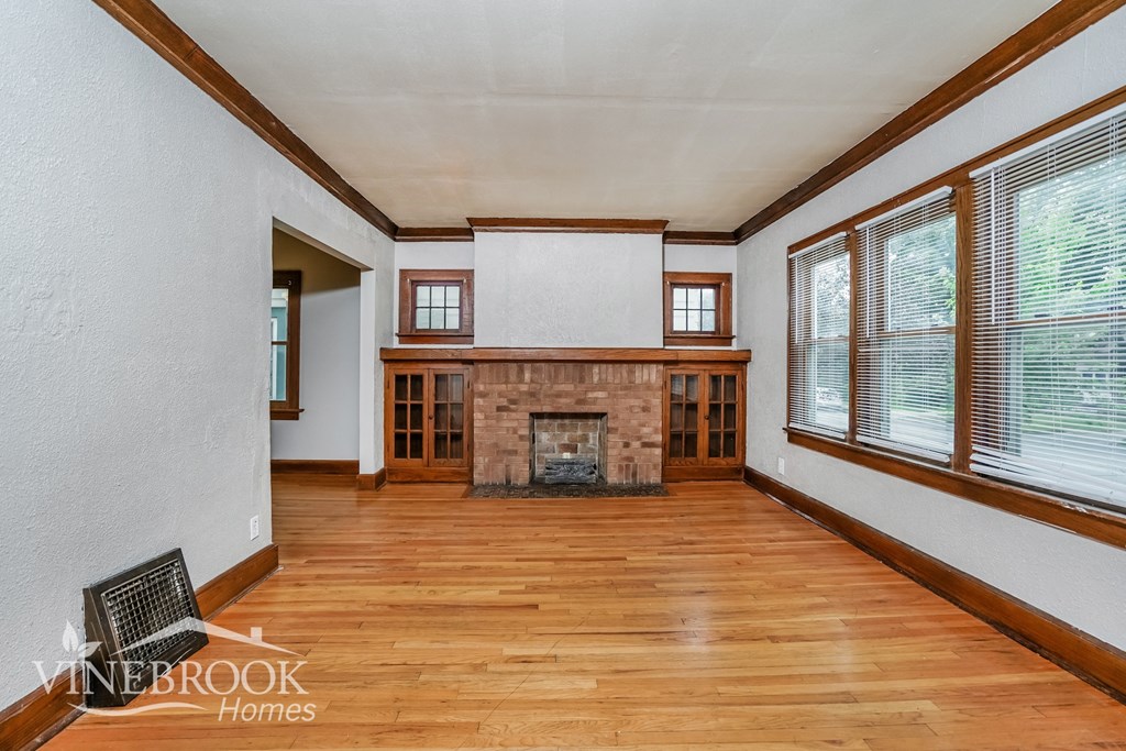 a living room with a fireplace and wooden floors and windows