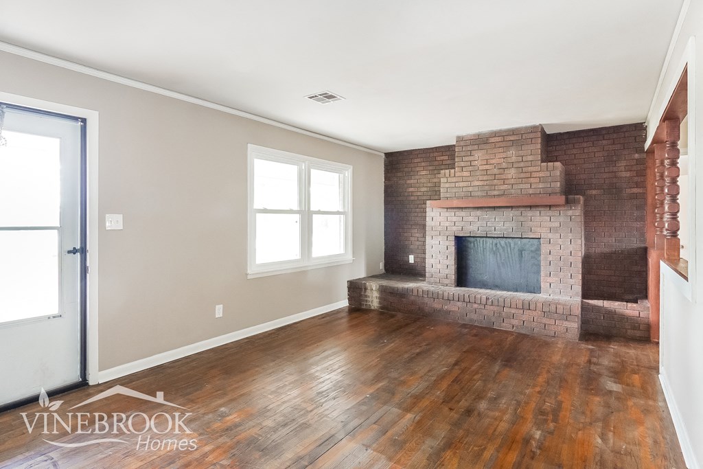 a living room with a brick fireplace and wooden floors
