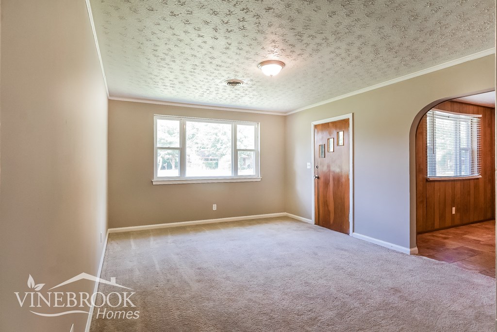 a living room with a carpeted floor and a wooden door and a white ceiling
