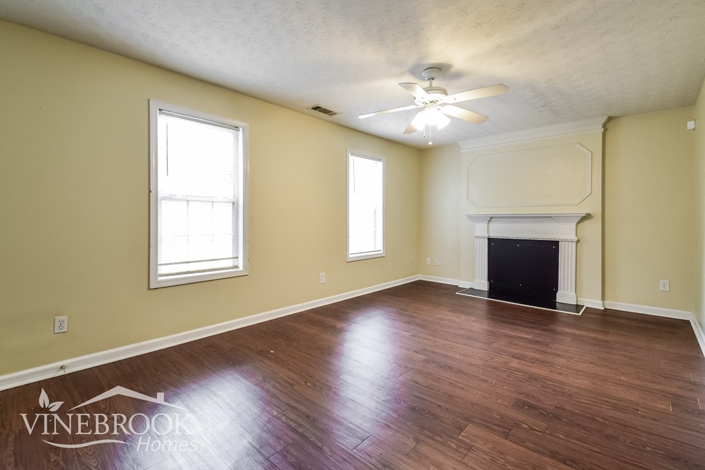 the living room of an empty house with wood floors and a fireplace