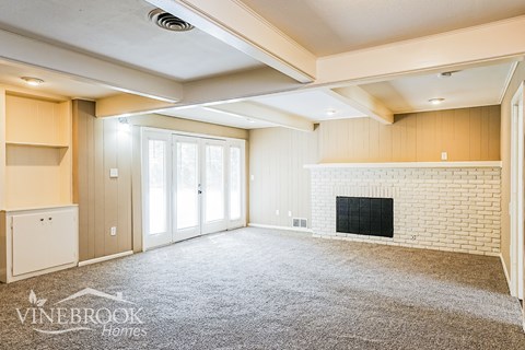 A living room with a fireplace and a carpet on the floor.