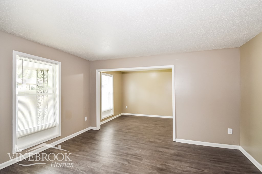A room with a window and a doorway leading to another room.