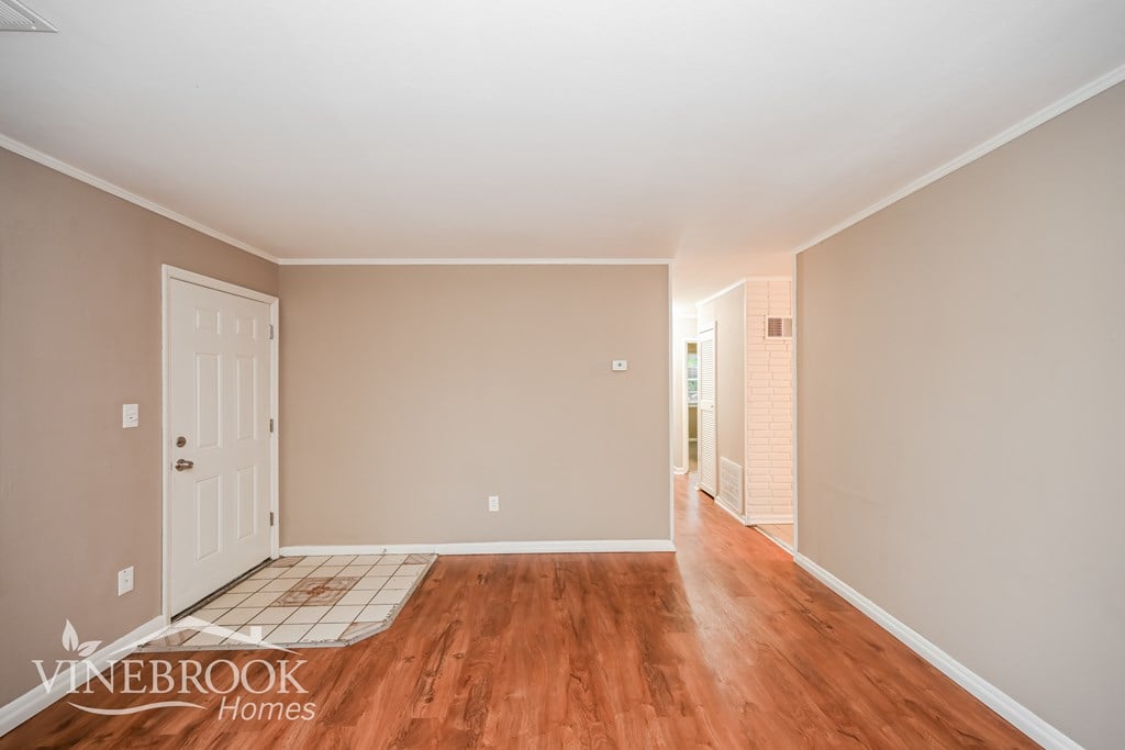 A room with wooden floors and a door on the left side.