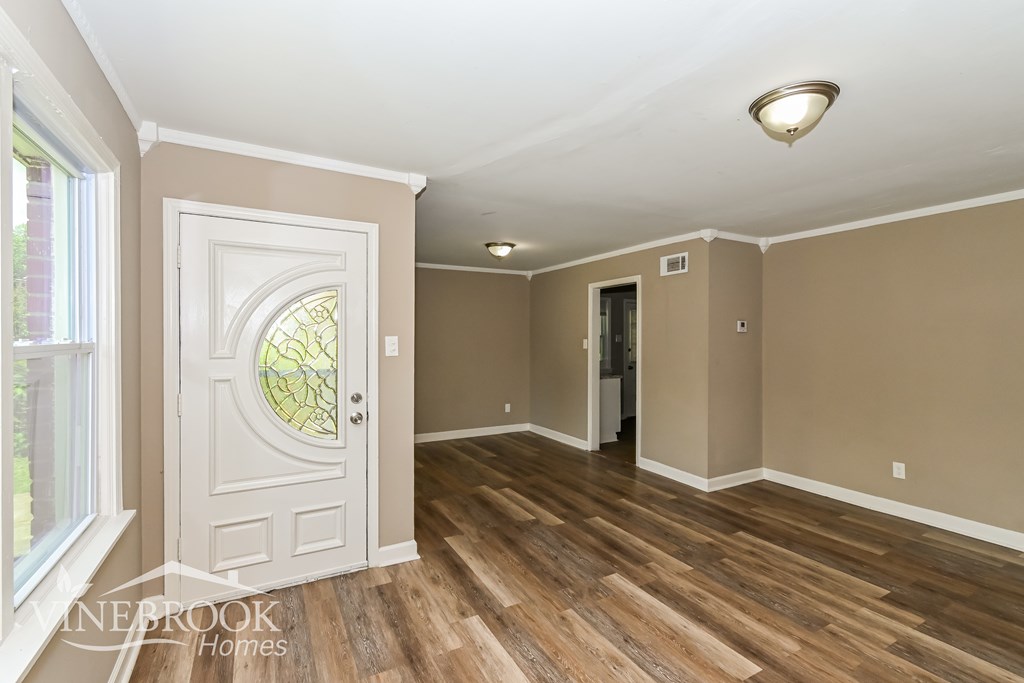 A room with a white door and wooden floors.