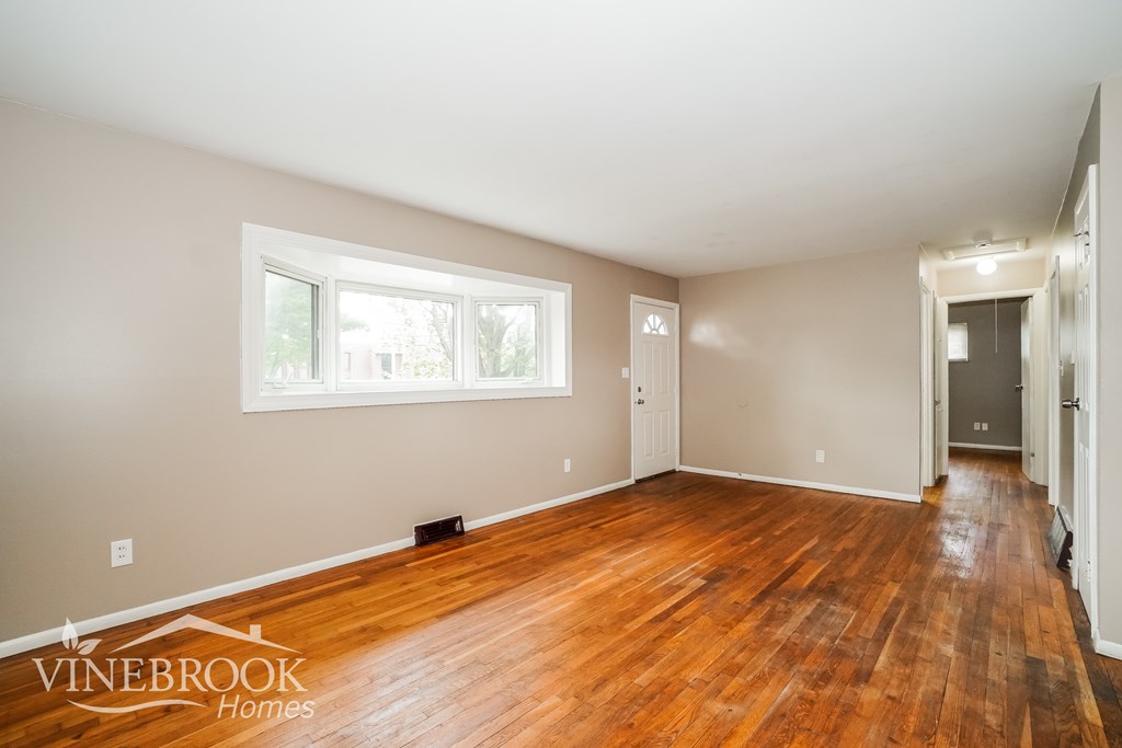 A room with wooden floors and a window is available for rent.