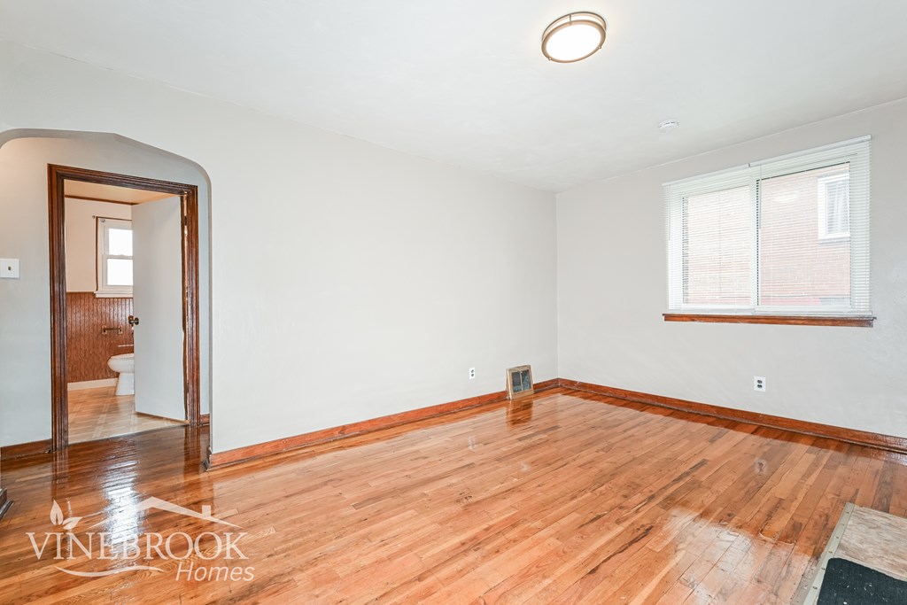 A room with wooden floors and a window with blinds.