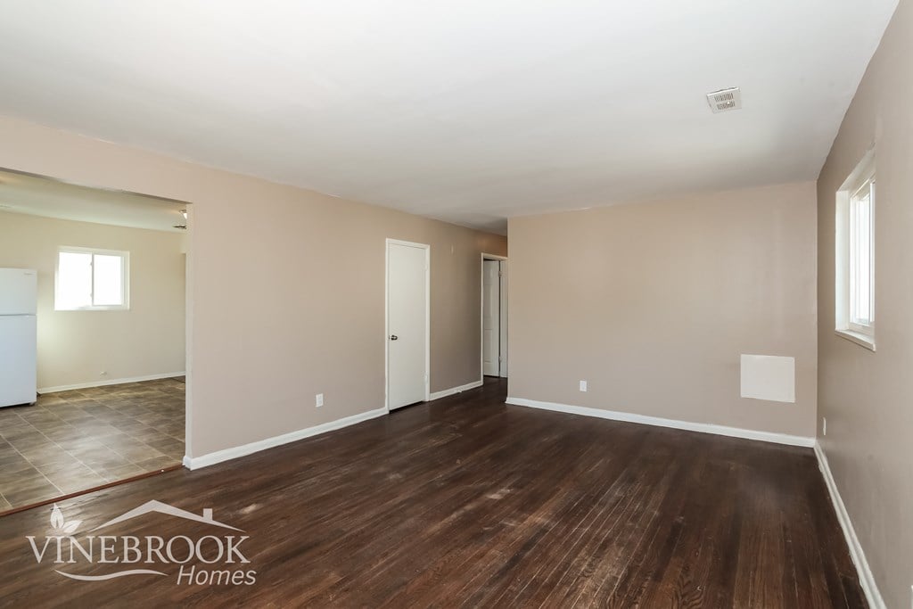 A room with wooden floors and a white ceiling with a window on the left side.