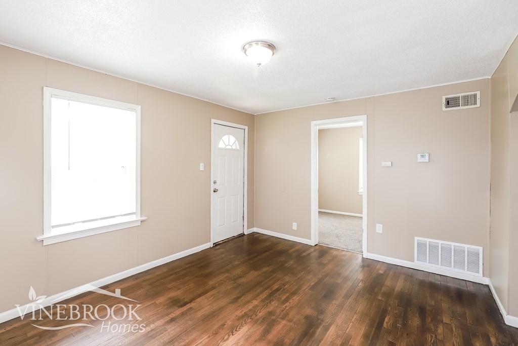 A room with wooden floors and a window on the left side.