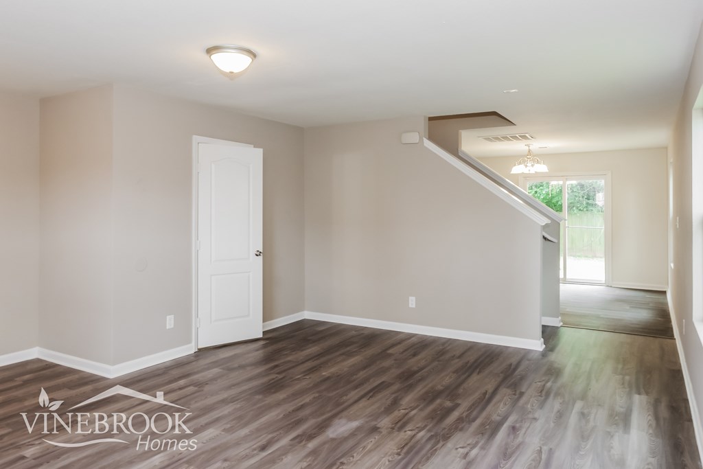 A room with a white door and a staircase leading to another room.