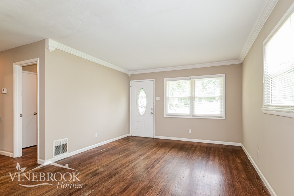 A room with wood flooring and a window with blinds.