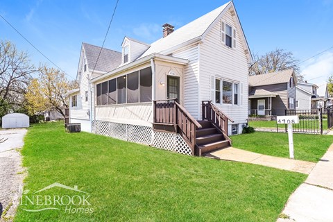 A two-story house with a white exterior and a brown front porch.