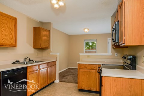 A kitchen with wooden cabinets and a Vinebrook Homes logo.