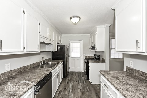 A kitchen with granite countertops and white cabinets.