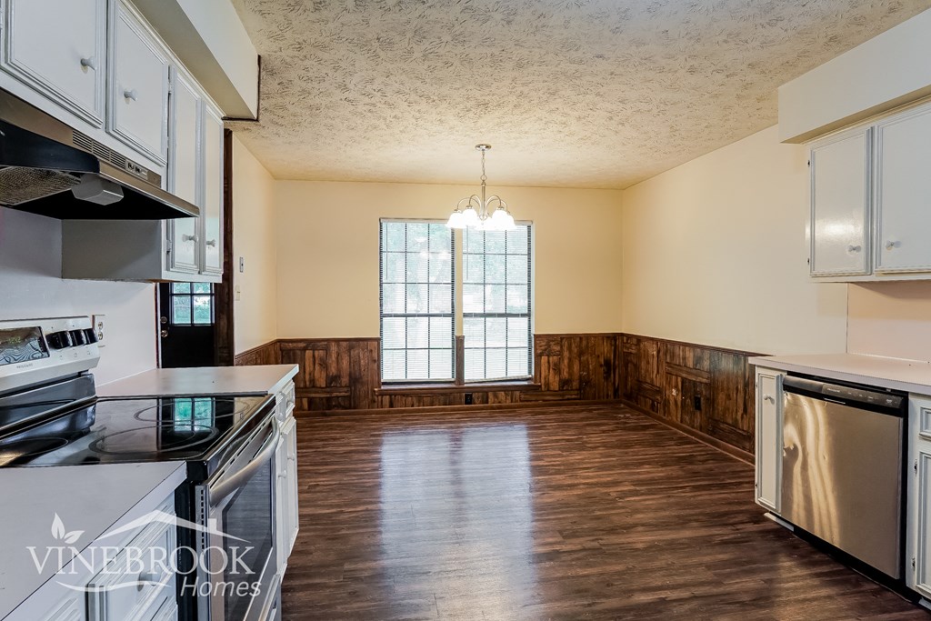 an empty kitchen with wood floors and a window
