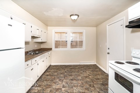 A kitchen with white appliances and a tiled floor.