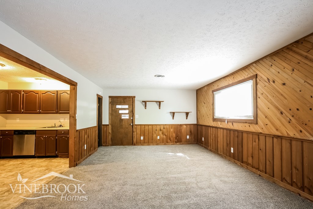 A large empty room with wooden walls and a window.