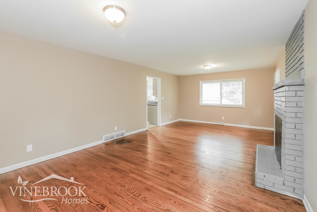 the living room and dining room with wood floors and a fireplace