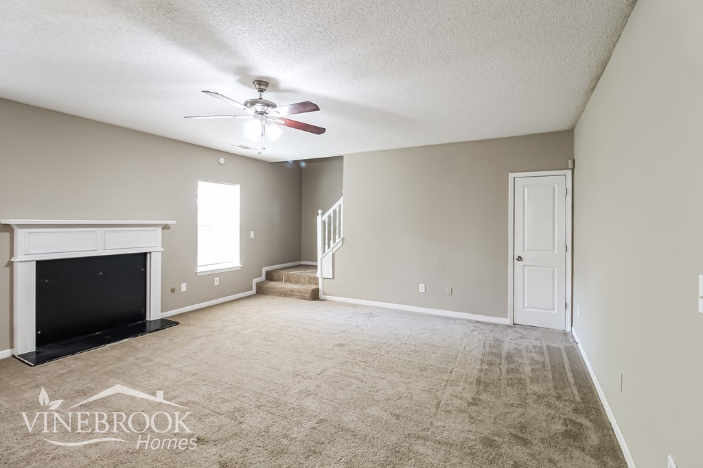 a living room with a fireplace and a ceiling fan